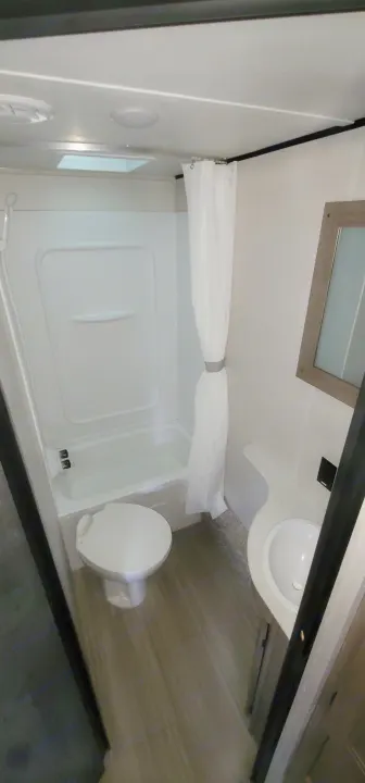 Compact RV rental bathroom with shower, toilet, and sink. Clean and functional interior for your travels.. Keystone Hideout 2021