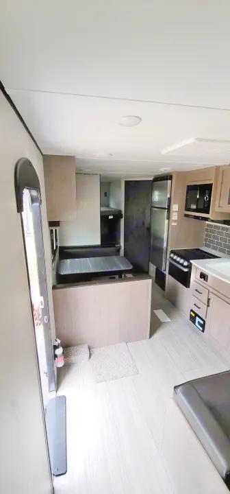 RV rental interior: modern kitchen, light wood-look floor, and a spacious living area, ideal for road trips.. Keystone Hideout 2021