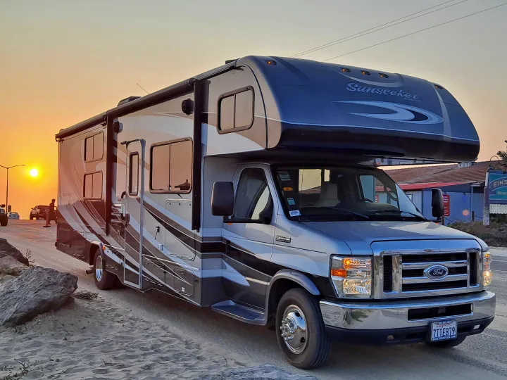RV rental: Sunseeker Class C motorhome on a sandy path by the ocean at sunset. Ford E-450 chassis visible.. Forest River Sunseeker 2018