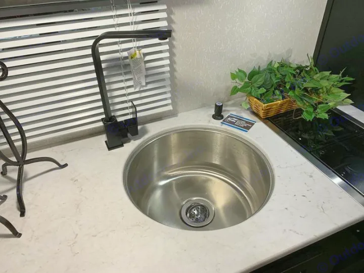 Compact RV rental kitchen with stainless steel sink, sleek black faucet, light counter & horizontal blinds.. Forest River Cherokee Wolf Pup 2022