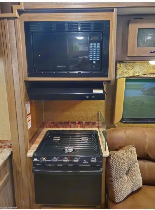 Enjoy your RV rental with this fully equipped kitchen: microwave, 3-burner stove, and hood in a travel trailer.. Coachmen Freelander 31BH 2017