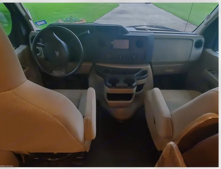 Spacious RV rental cockpit view: beige seats, Ford dashboard with screen, and center console with cup holders.. Coachmen Freelander 31BH 2017