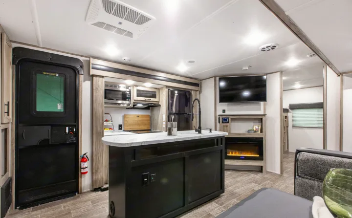 Spacious, modern RV rental interior featuring a full kitchen with island, living area with TV & fireplace.. Forest River Cherokee Wolf Pack 2021