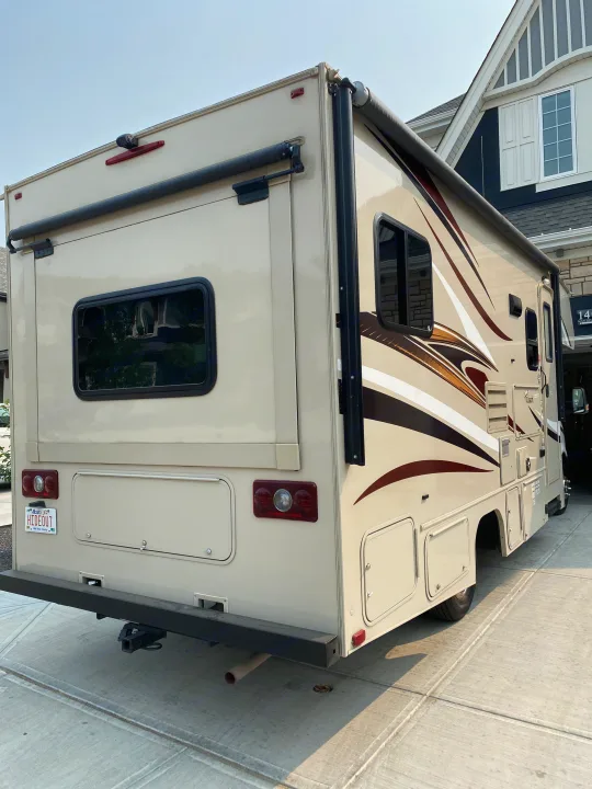 Beige Class C RV rental, with graphic stripes, parked on a driveway, ready for travel or camping adventures.. Coachmen Prism 2016