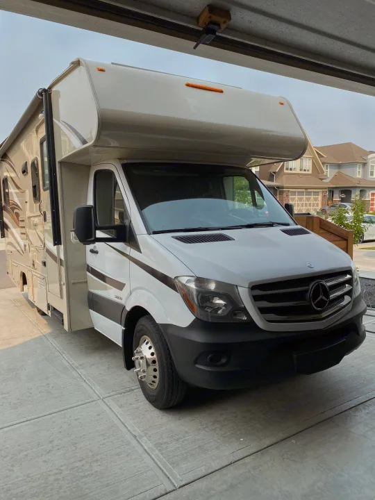 This pristine white and beige Mercedes Sprinter RV rental is ready for your next adventure, parked on a concrete driveway.. Coachmen Prism 2016