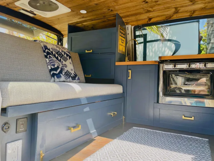 Cozy RV rental interior: Custom van features a built-in bed/couch, kitchen with oven, storage, and beautiful wood ceiling.. Chevrolet Astro Van AWD 2003
