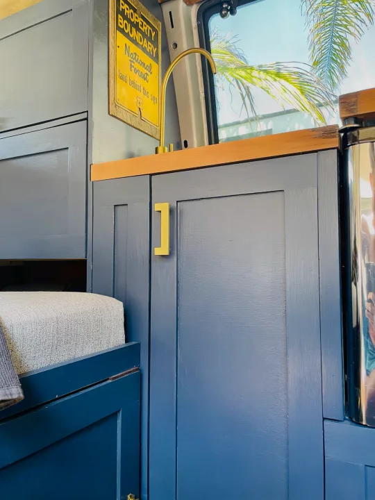 Stylish RV rental interior with blue cabinetry, a brass faucet, and wood accents. Enjoy comfy travels!. Chevrolet Astro Van AWD 2003