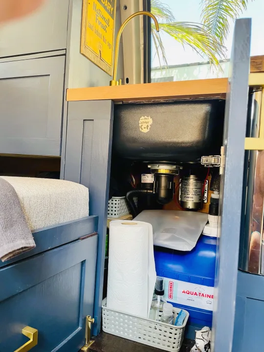 Compact rv rental kitchen: Kohler sink, SHURFLO pump, and AQUA-TAINE tank in blue cabinetry. Ready for adventure!. Chevrolet Astro Van AWD 2003