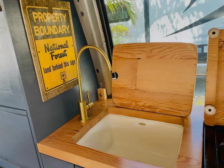 RV rental's clever kitchen setup: Kohler sink, brass faucet, wood counters, and a unique National Forest sign.. Chevrolet Astro Van AWD 2003