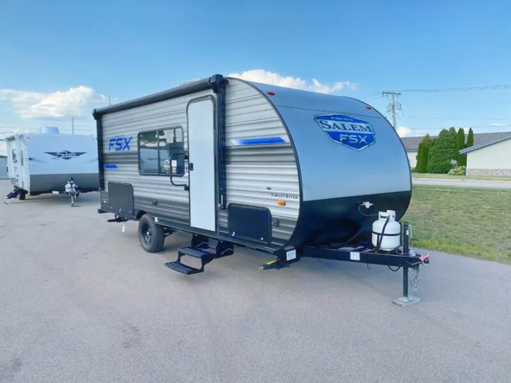 A grey & black Salem FSX travel trailer, perfect for RV rental, parked outdoors with another RV visible.. Forest River Salem 2021