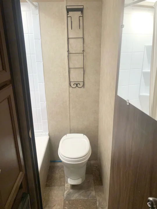 Compact RV rental bathroom with toilet, tub/shower, and wall rack for storage, maximizing space.. Coachmen Clipper 2015