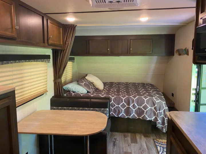 Cozy RV rental interior showing a bed, dinette, and ample overhead storage. Ready for your next adventure!. Starcraft Autumn Ridge 2018