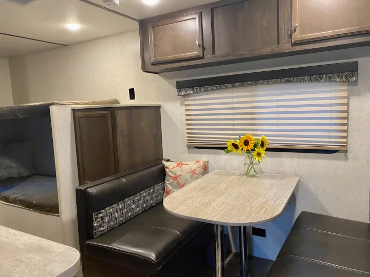 Inside a modern RV rental: dining area with a table, benches, and bunk beds. Perfect for family travel.. Starcraft Autumn Ridge 2018