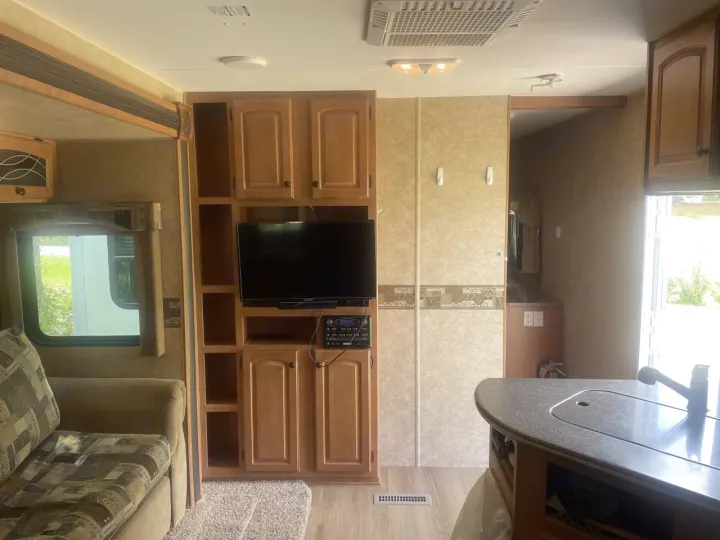 Spacious RV rental interior featuring a cozy living area with sofa, entertainment system, and kitchen counter.. Heartland North Country Lakeside 2011