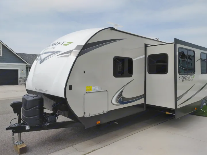 White and gray RV, great for an rv rental, parked with an extended slide-out in a residential driveway.. Starcraft Travel Trailer 2021