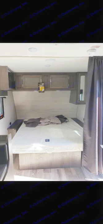 Inside an RV rental: a clean, new bedroom with a large mattress, overhead cabinets, and wood flooring. Perfect for your travels.. Jayco Jay Flight 2021