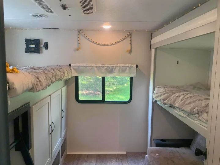 Inside a cozy RV rental: two sets of bunk beds, storage cabinets, and a bright window. Ideal for family trips.. Forest River Vibe 2021