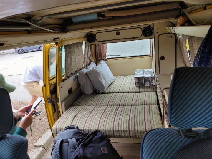 Cozy camper van interior: striped beds, pillows, and storage. Perfect RV rental for road trips and adventure.. Volkswagen Westfalia 1982