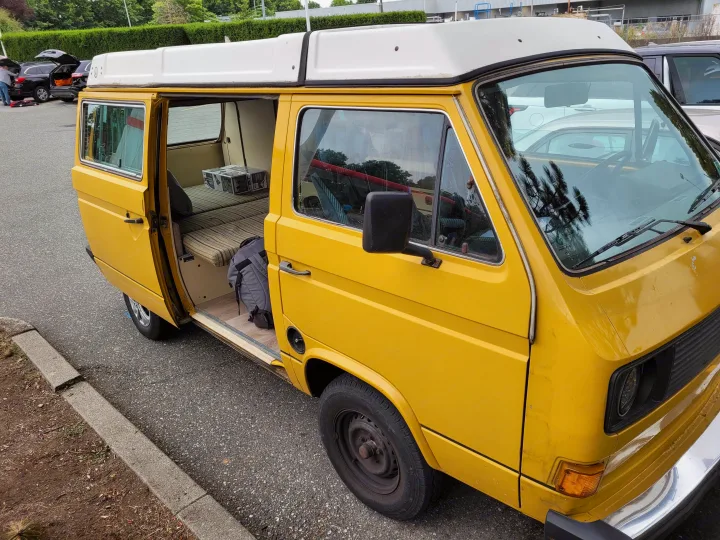Yellow retro camper van with open side door, showing interior conversion. Perfect for your next rv rental adventure!. Volkswagen Westfalia 1982