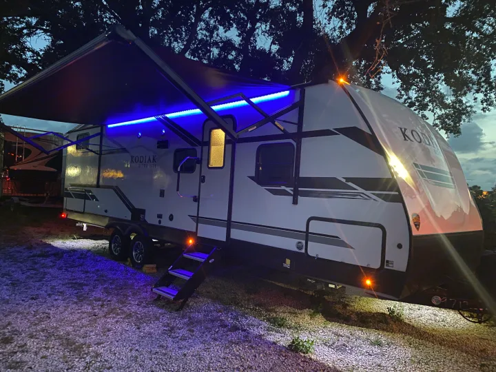 Experience the magic of an RV rental with this Kodiak travel trailer glowing under blue lights at dusk.. Dutchmen Kodiak 2021