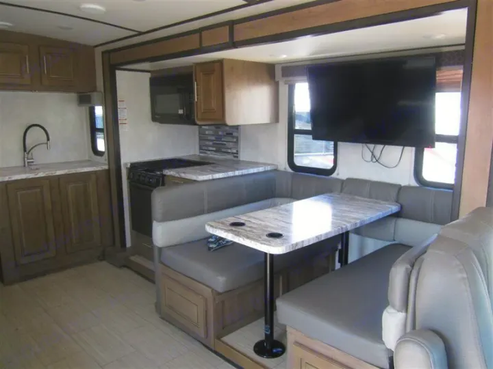 Modern RV rental interior with a well-equipped kitchen, U-shaped dinette, and large mounted TV.. Forest River Other 2020