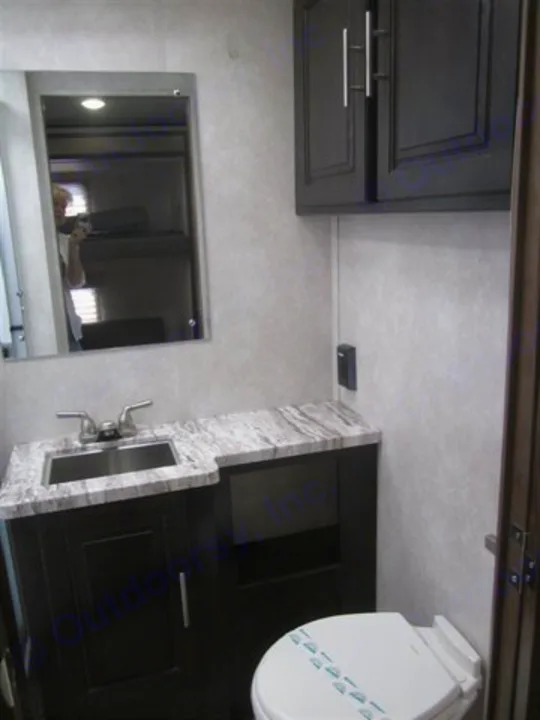 Inside an RV rental: a compact bathroom with a modern sink, dark vanity, toilet, and mirrored cabinet.. Forest River Other 2020