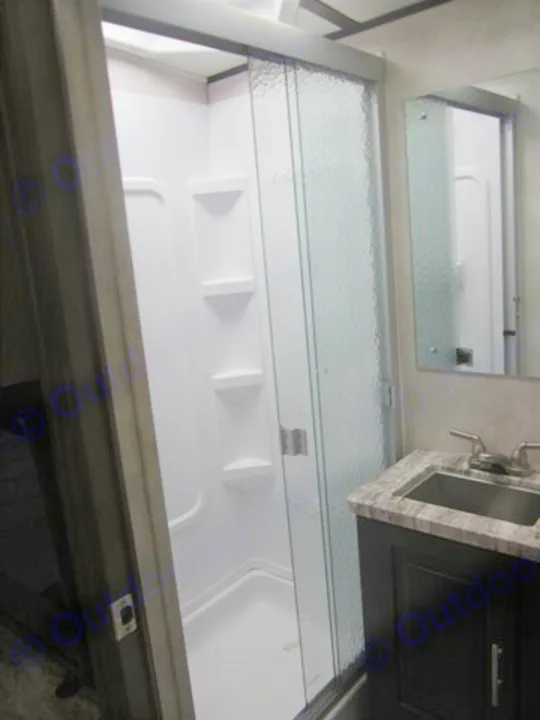 RV rental: Bright, compact bathroom with a white shower enclosure, glass door, dark vanity, sink, and mirror.. Forest River Other 2020