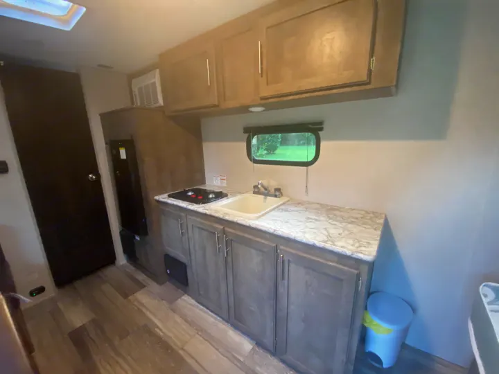 Compact RV rental kitchen with sink, stovetop, and cabinets, perfect for travel trailer adventures.. K-Z Manufacturing Sportsman Classic 2021