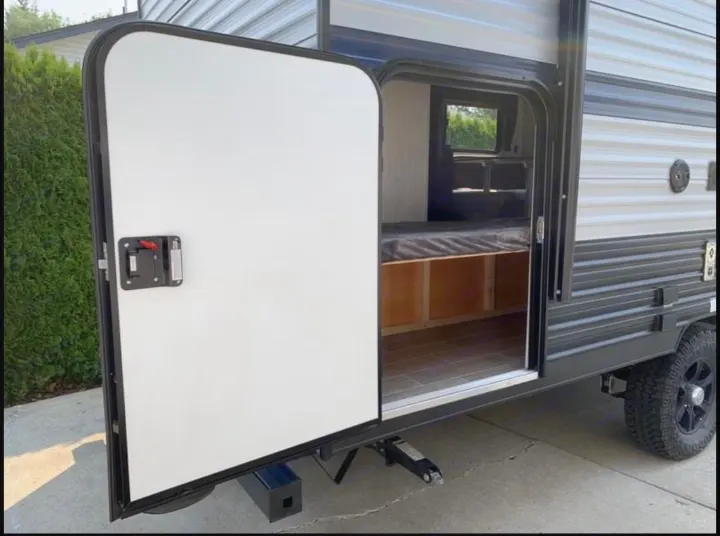 Side view of an RV rental with its door open, showcasing a clean interior with bunk & storage. Features rugged tires & stabilizer jacks.. Forest River Wolf Pup 2020