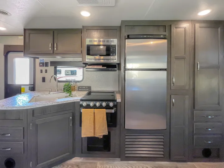 Spacious RV rental kitchen featuring modern gray cabinets, a stainless steel microwave, stove, fridge, and a functional sink area.. Jayco Jay Flight 2021