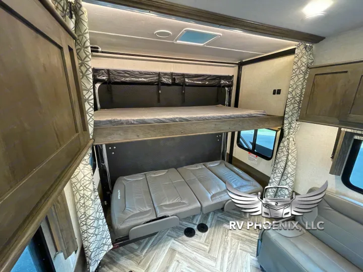 Modern RV rental interior with drop-down bunk beds, convertible seating, and patterned curtains. Ideal for flexible trips.. Forest River Stealth 2021