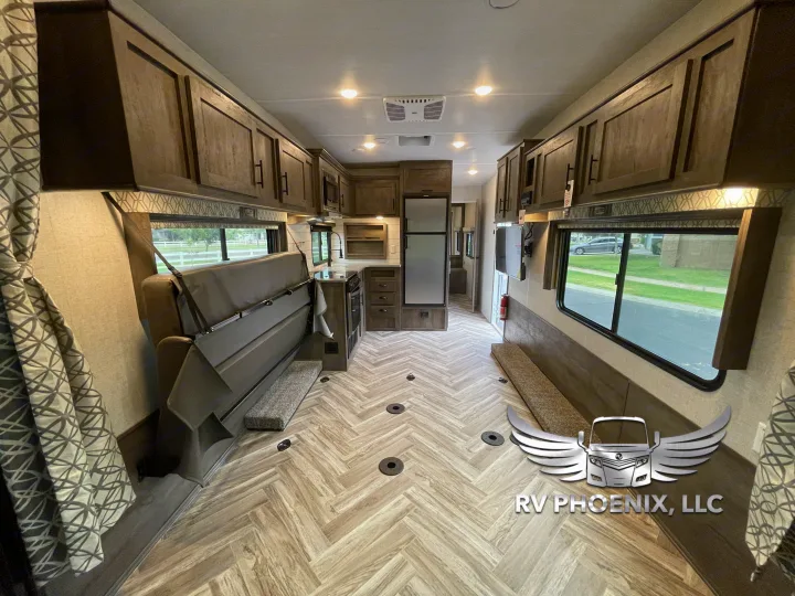 Spacious RV rental interior featuring a modern kitchen, versatile seating/bed, and wood-look herringbone flooring.. Forest River Stealth 2021