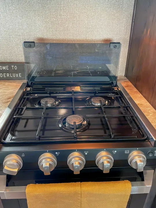 RV rental: Clean, black gas stove with three burners, open glass cover, and oven, ready for use.. Jayco Jay Flight 2021