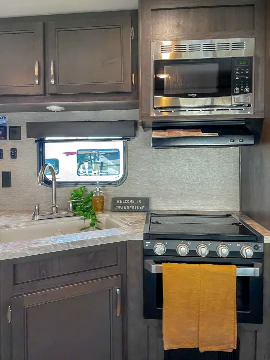 Step inside this RV rental's well-equipped kitchen: microwave, stove, sink, & dark cabinets provide comfort on the go.. Jayco Jay Flight 2021