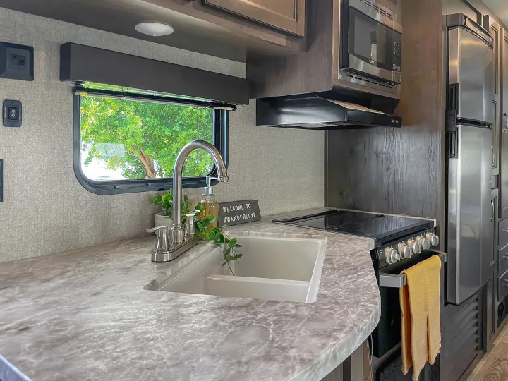 RV rental kitchen with modern sink, gas stove, microwave, and fridge. Enjoy the view from the window!. Jayco Jay Flight 2021