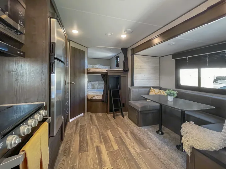 Inside an RV rental: a compact living space featuring a kitchen, dining booth, and dedicated bunk beds for travelers.. Jayco Jay Flight 2021