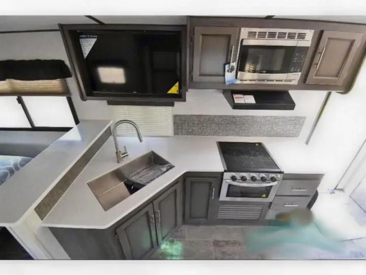 Spacious RV rental kitchen featuring a large sink, full stove/oven, microwave, and overhead TV. Ideal for travel.. Crossroads RV Sunset Trail Super Lite 2021