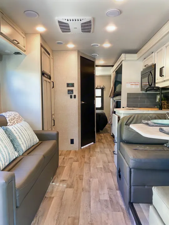 Bright RV rental interior featuring a full kitchen, comfortable living area, dining booth, and rear sleeping spaces.. Entegra Coach Other 2022