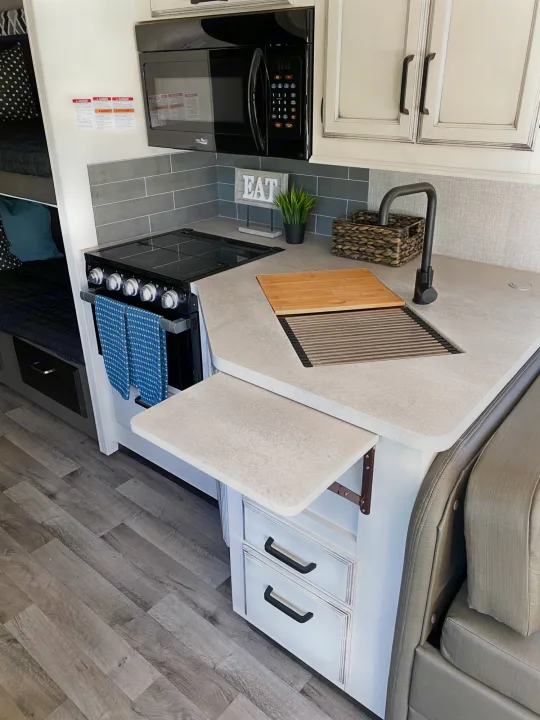 This RV rental boasts a stylish, compact kitchen with a microwave, stove, integrated sink, extendable counter, and nearby bunks.. Entegra Coach Other 2022