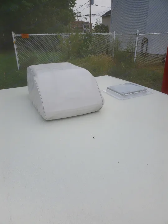 Top-down view of an RV rental roof showing a white AC unit cover & roof vent.. Viking 1906st 2004