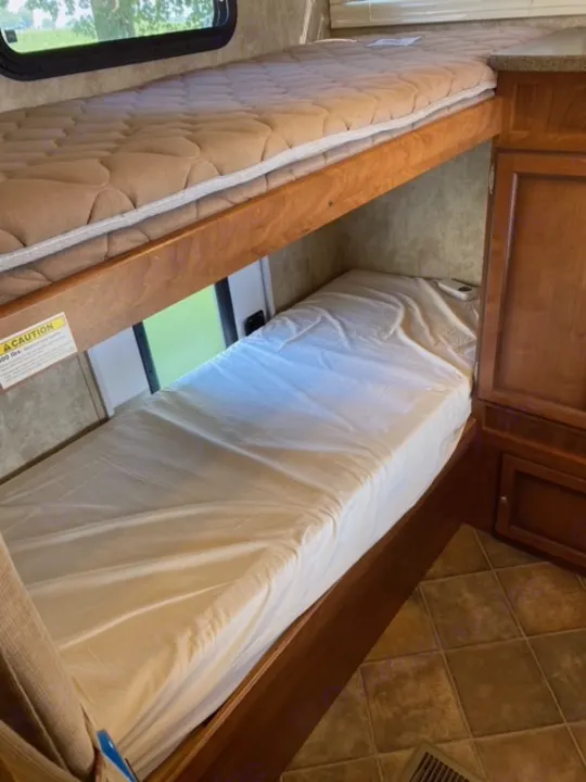 RV rental sleeping area showing two mattresses, wooden divider, and overhead cabinets.. Other Passport 2012