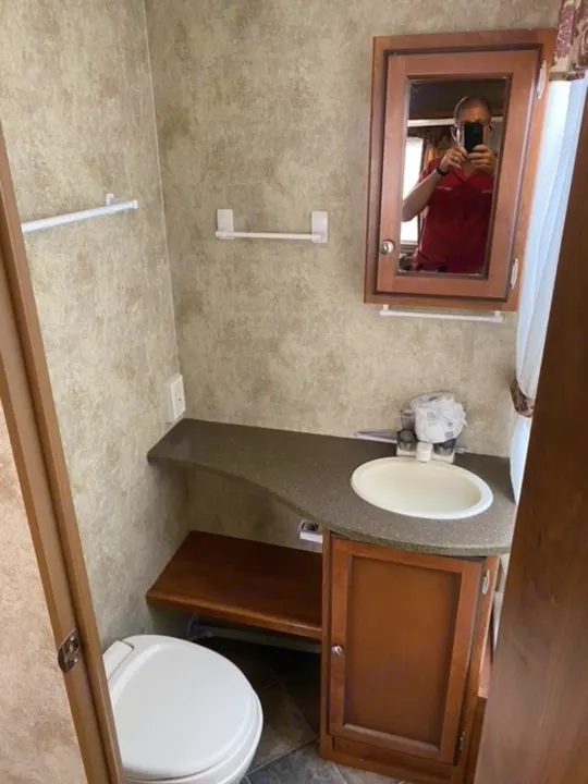 Inside this compact RV rental bathroom: mirror, sink, toilet, and storage cabinet, complete with small towel bars.. Other Passport 2012