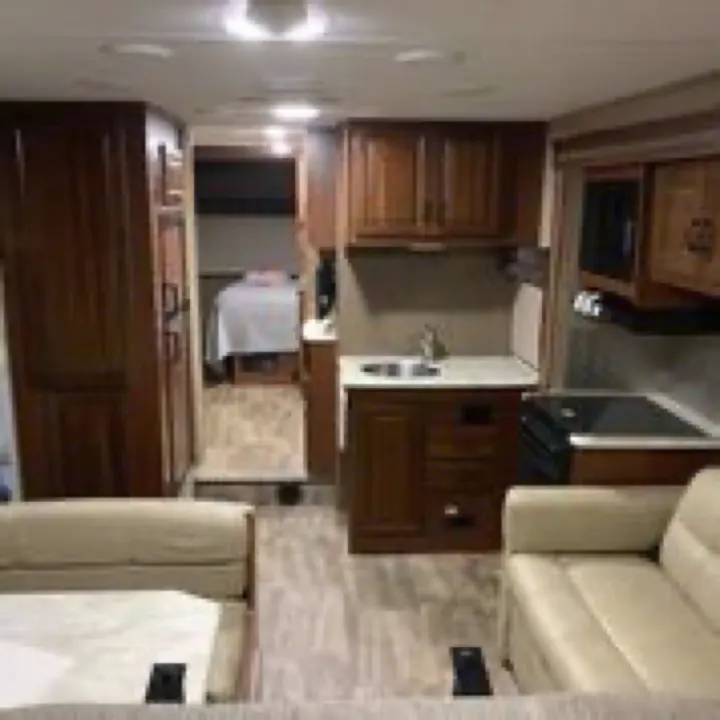 RV rental interior features a bright living area, well-equipped kitchen, and a spacious bedroom with wood cabinetry.. Forest River Sunseeker 2017