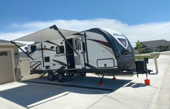 White Mallard travel trailer rv rental with extended awning & stability jacks on a concrete pad. Ready for your next trip.. Heartland Other 2018