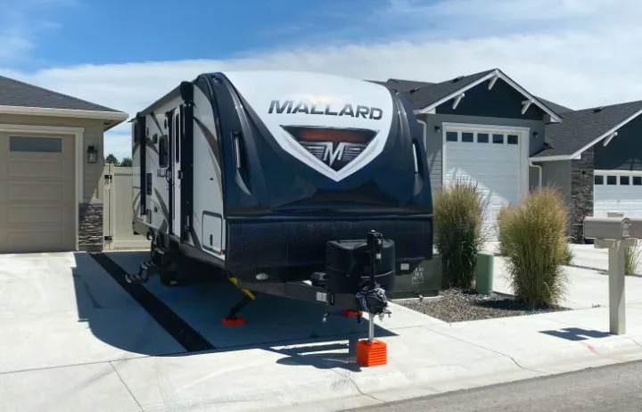 MALLARD travel trailer (an RV rental) parked on a paved residential driveway. Set up with orange blocks.. Heartland Other 2018