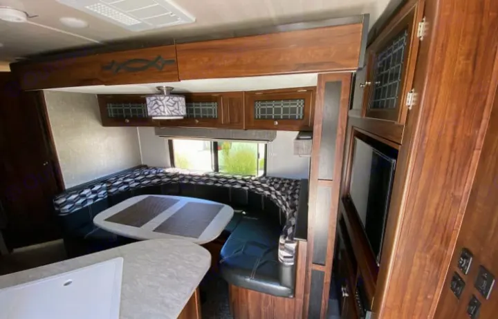 Spacious RV rental interior with U-shaped dinette, overhead cabinets, and entertainment center. Perfect for road trips.. Heartland Other 2018