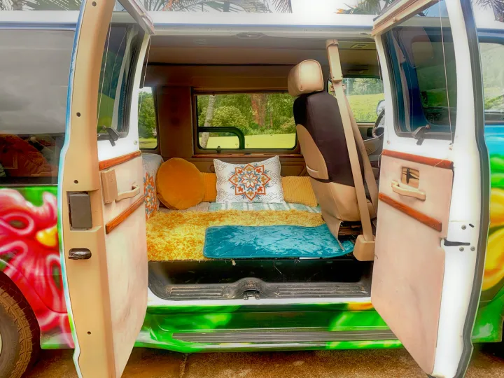 Colorful rv rental camper van interior: open doors reveal a cozy bed with vibrant pillows, ready for adventure.. Dodge Ram 1500 1999