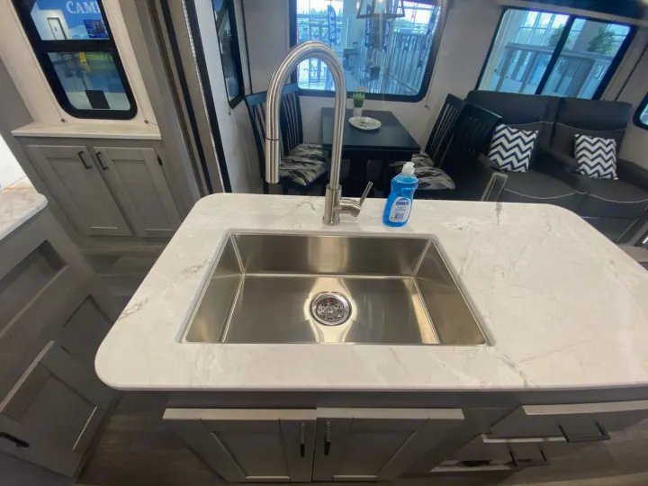 Comfy RV rental interior: kitchen island with sink, dining table, and living area with patterned pillows.. Heartland RVs Mallard 2021