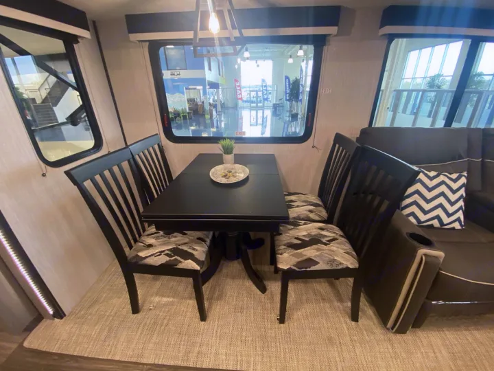 Comfortable RV rental interior: dark dining table, four patterned chairs, and cozy sofa. Ideal for your next journey.. Heartland RVs Mallard 2021