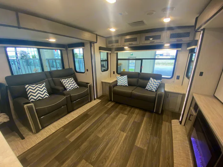 Spacious RV rental interior with dual sofas, modern decor, and a cozy fireplace, perfect for travel comfort.. Heartland RVs Mallard 2021